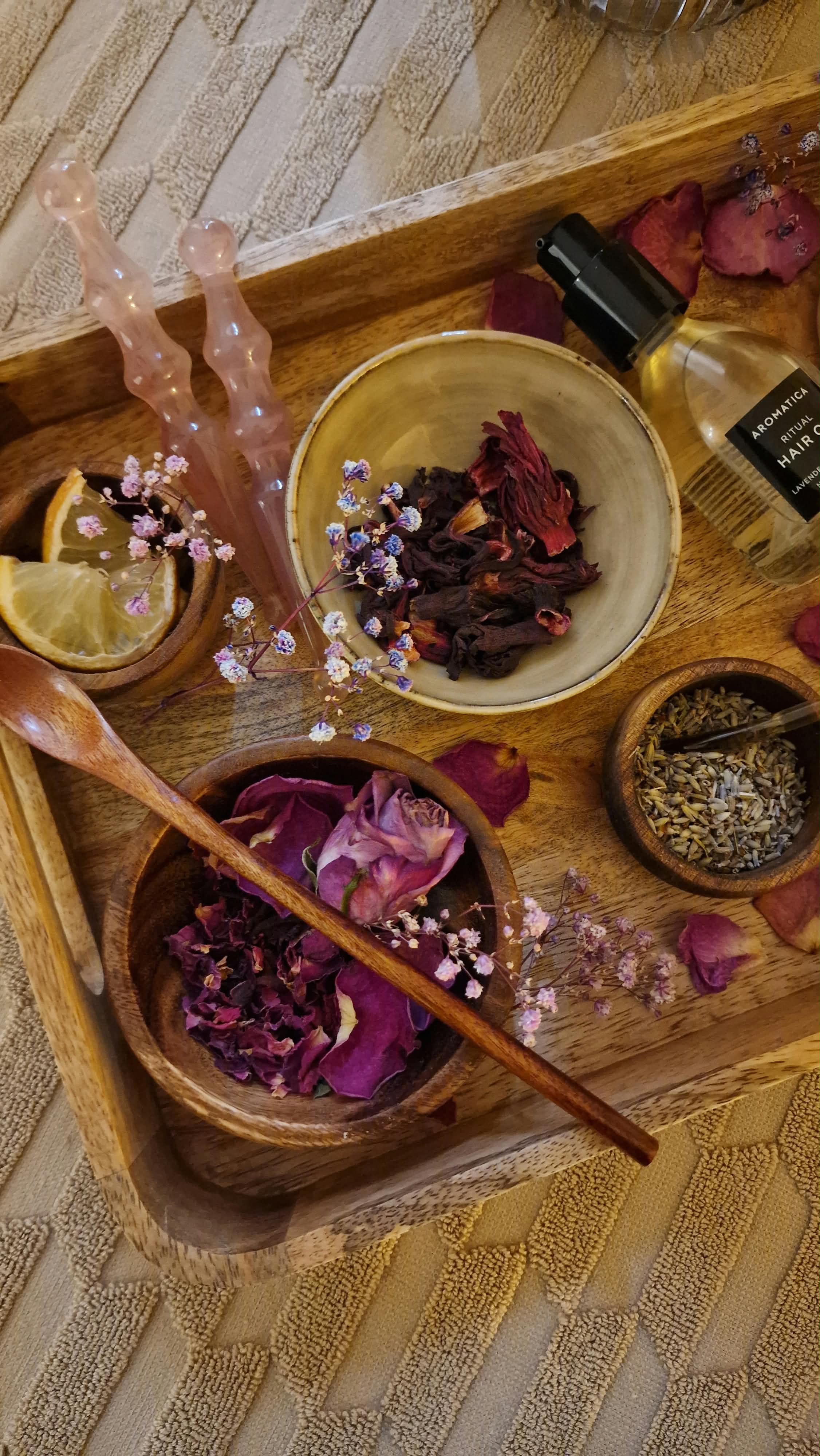 Gua-Sha-Steine, Botanicals und Haaröl auf einem Holztablett